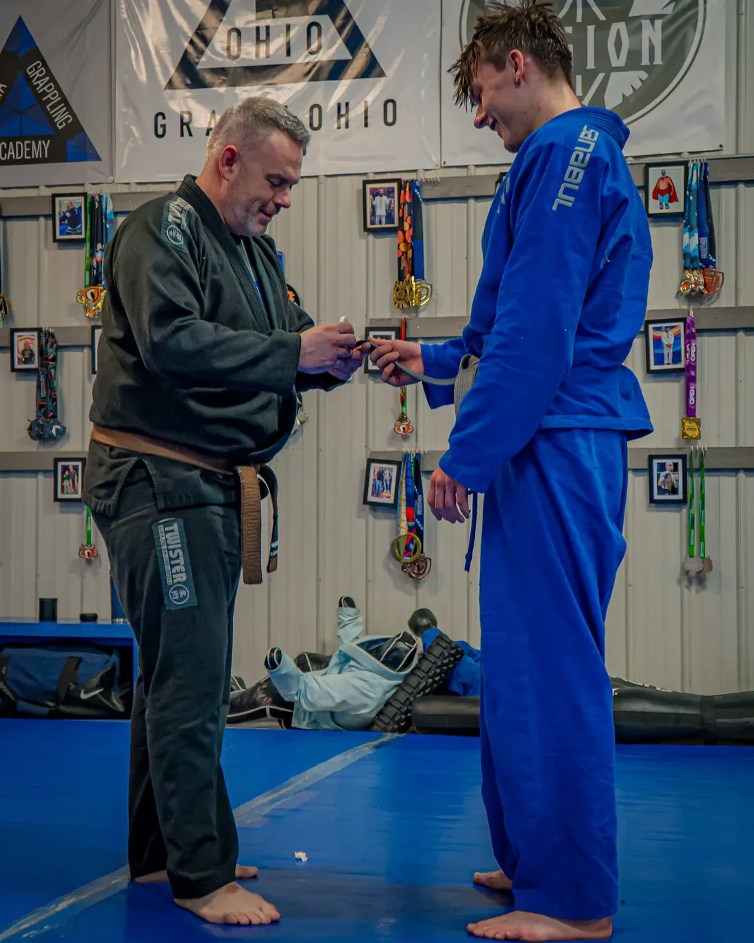 A coach presenting a new belt to a student at Delta Grappling Academy