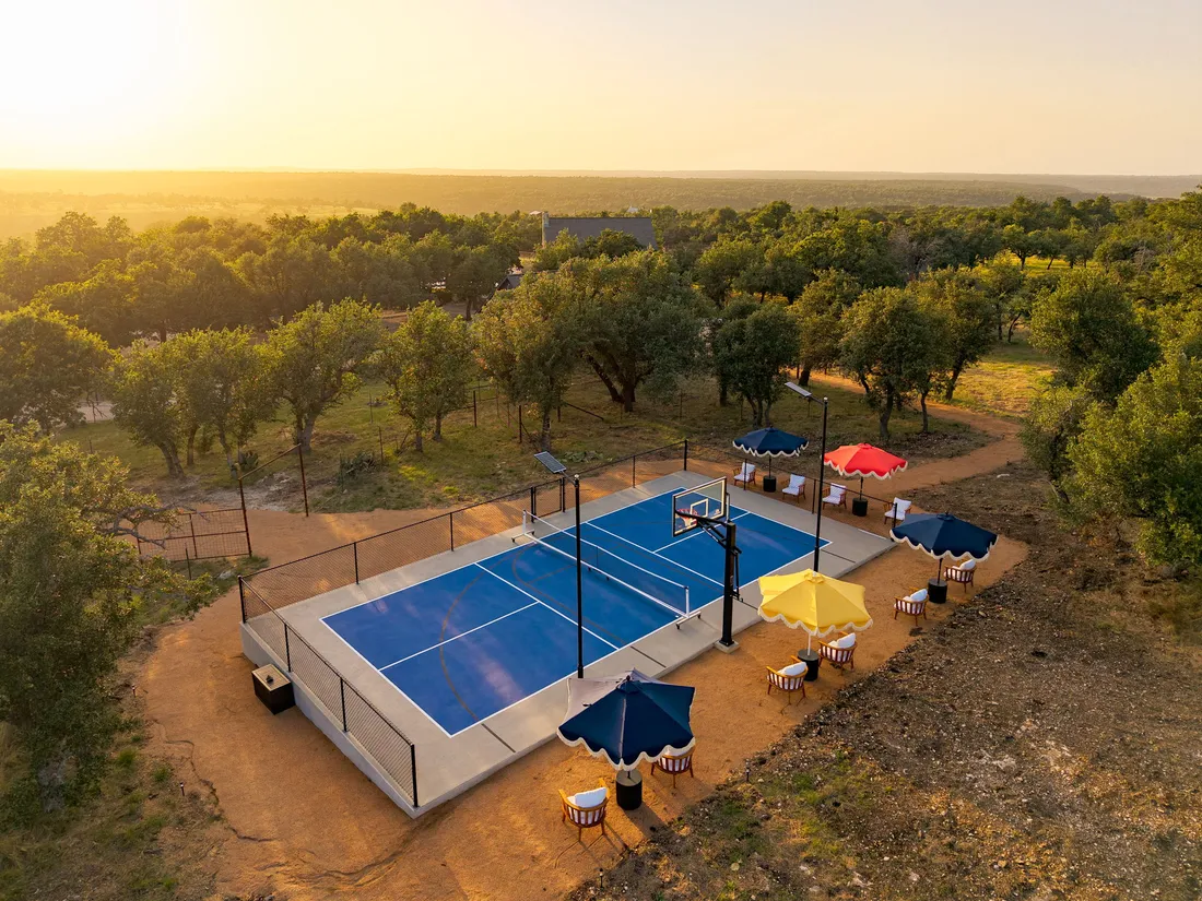 Pickleball court on acreage with shade and seating, aerial