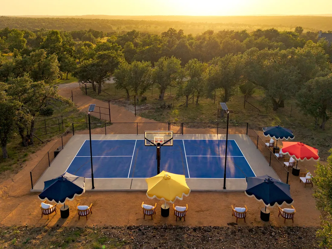 Pickleball court with umbrella seating, aerial at golden hour