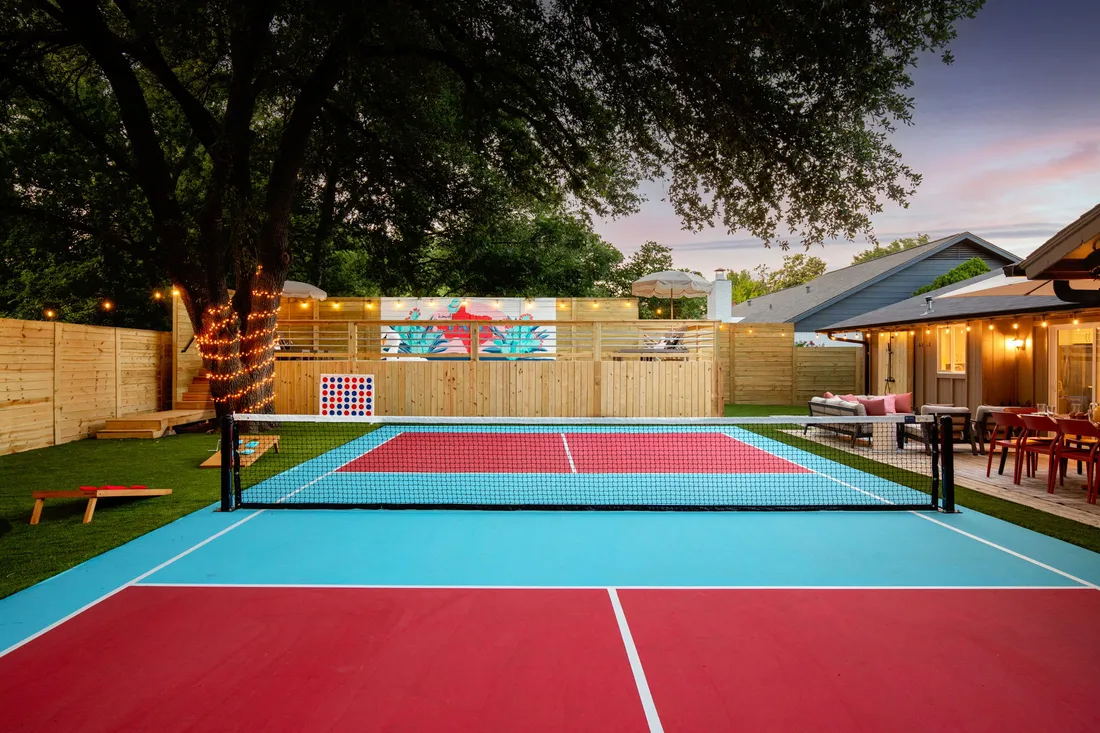 Pickleball court in red and teal with privacy fence and mural