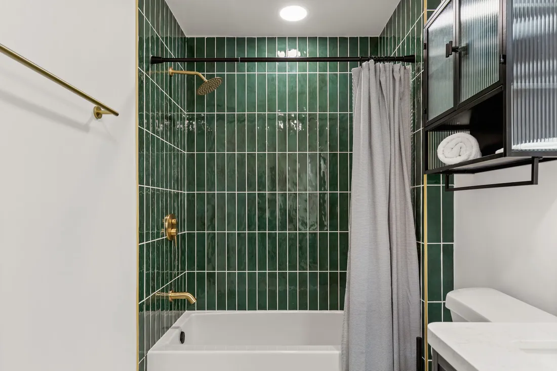 Bathroom in green tile with brass fixtures