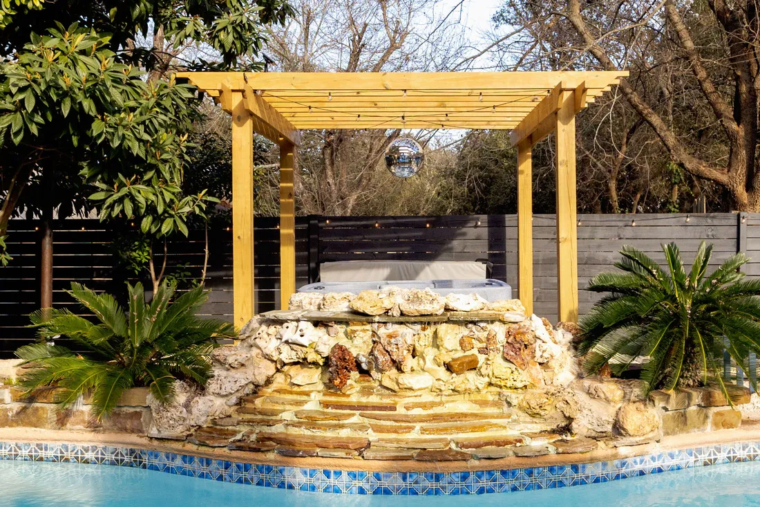 Rock waterfall into the pool under a cedar pergola
