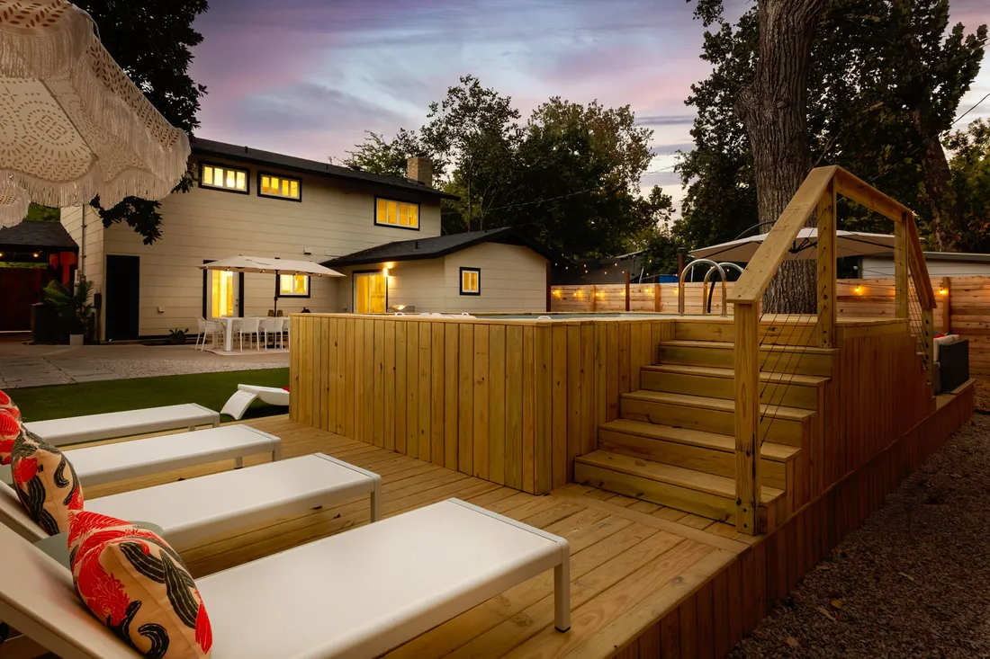 Raised wood deck with built-in stairs and loungers at dusk
