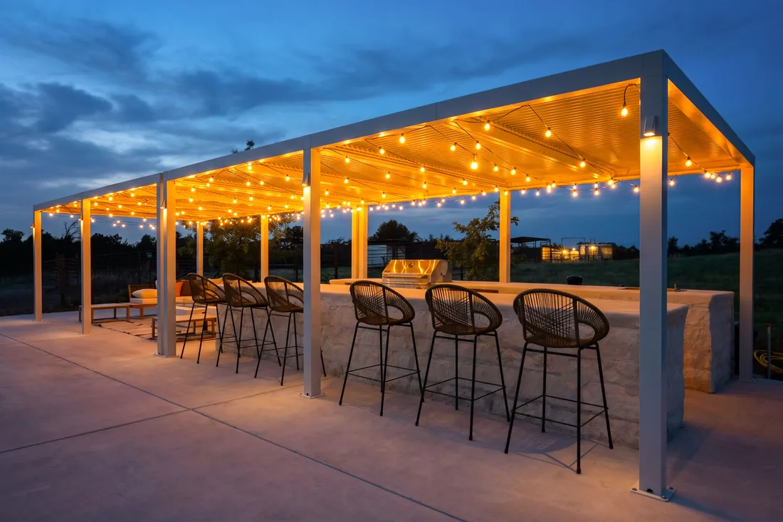 Outdoor bar pavilion with concrete counters and string lights at dusk, Fredericksburg