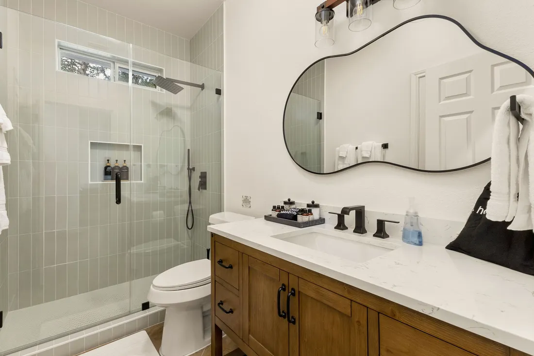 Bathroom with a glass shower, a wood vanity and a sculpted mirror
