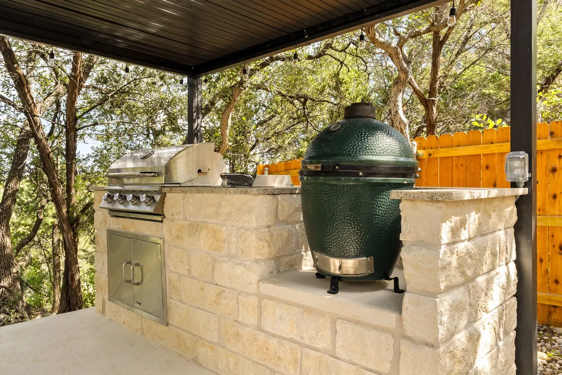 Outdoor kitchen in limestone with a grill and kamado under a steel roof, Wimberley