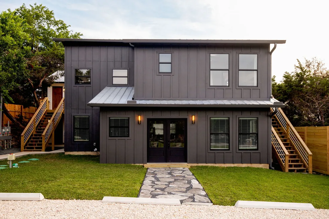 Two-story exterior refreshed in dark board and batten with new stairs and a stone path