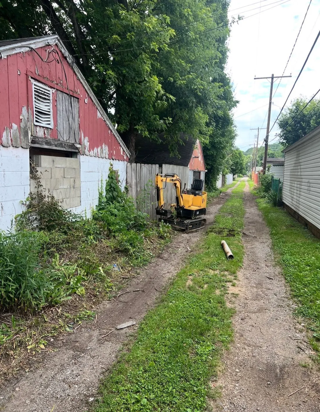 A mini excavator working the ground beside a property