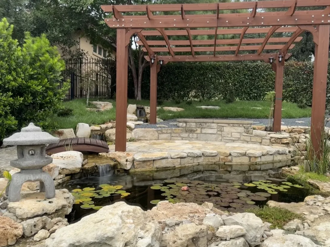 Koi pond under a pergola with a stream running into it, built by WaterScape, ATX