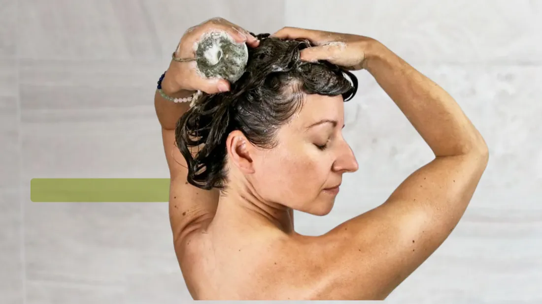 Mujer lavándose el pelo con un champú sólido Nutwa en la ducha