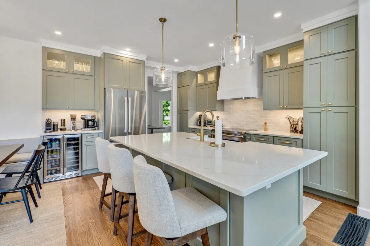 Rose Finch Cir main photo — Two-tone open-concept kitchen with green base cabinetry, white uppers, and a central island.