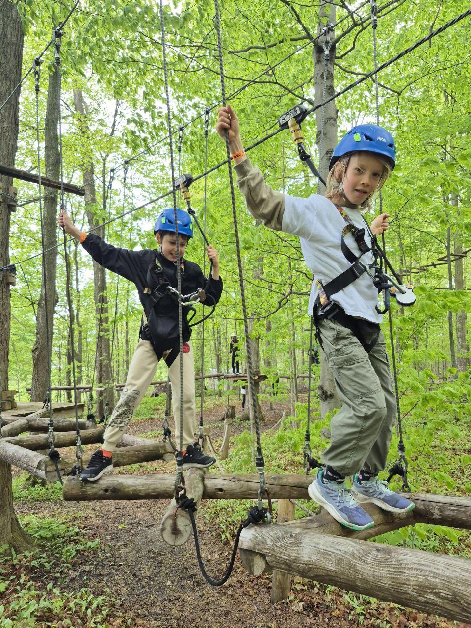 Two Evergreen students taking on a treetop ropes course together