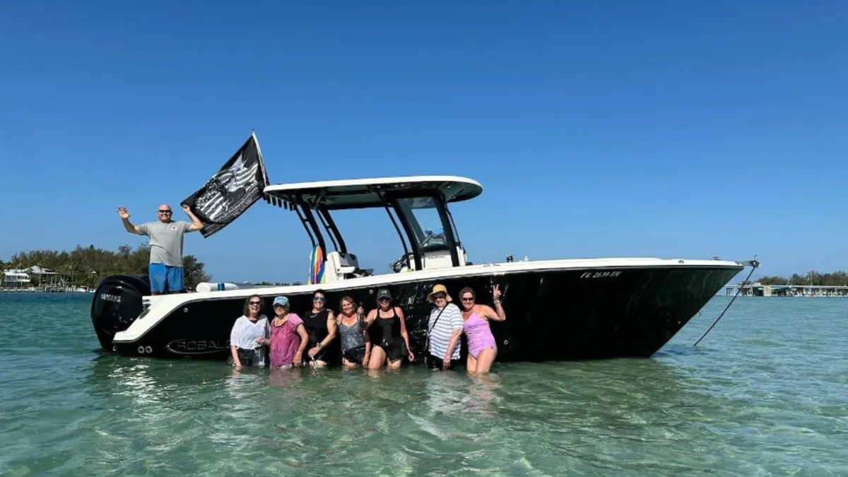 Centaur Adventures guests gathered beside the operator's center-console charter boat in shallow Anna Maria Island water.