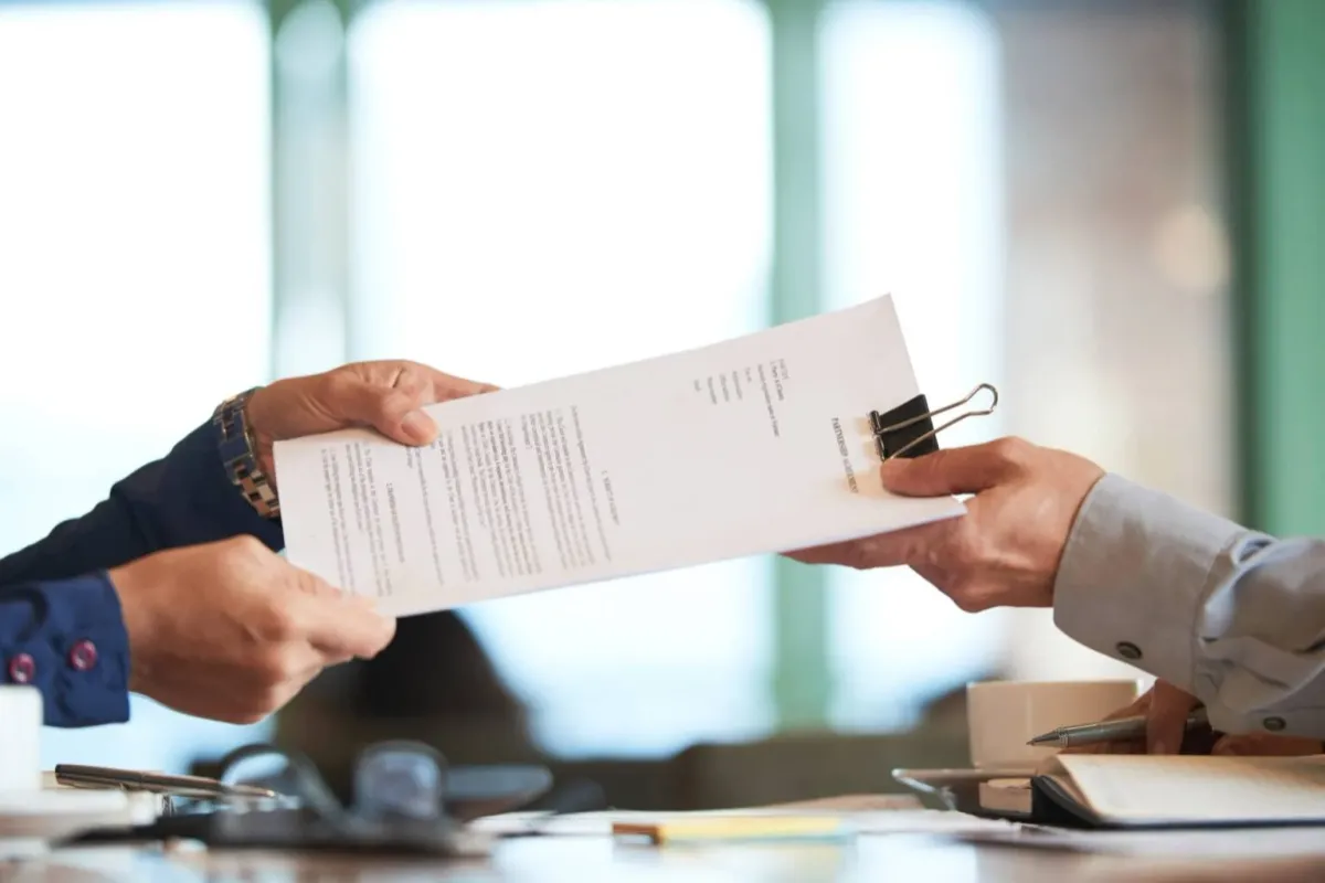A professional handing an important document to a client