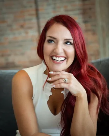 Jennifer Farhad smiling, with red hair and a white sleeveless blouse