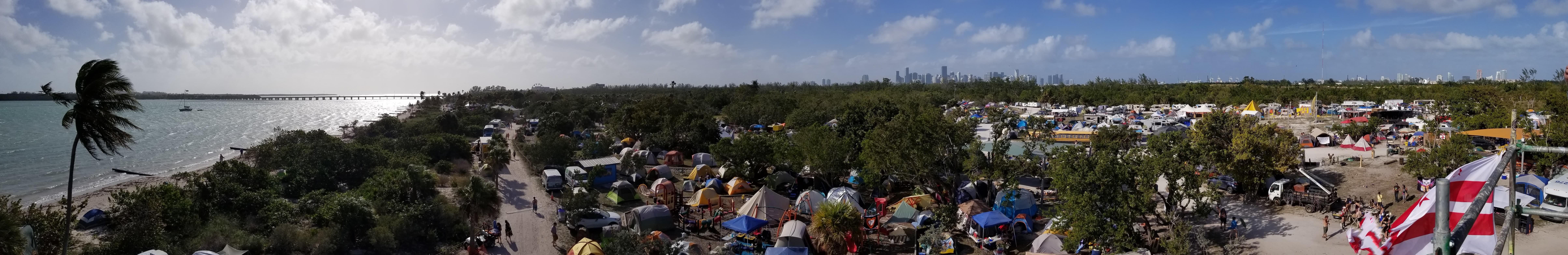 Panoramic view over the Love Burn campground on Virginia Key, with tents, RVs and the waterfront, photographed in 2020