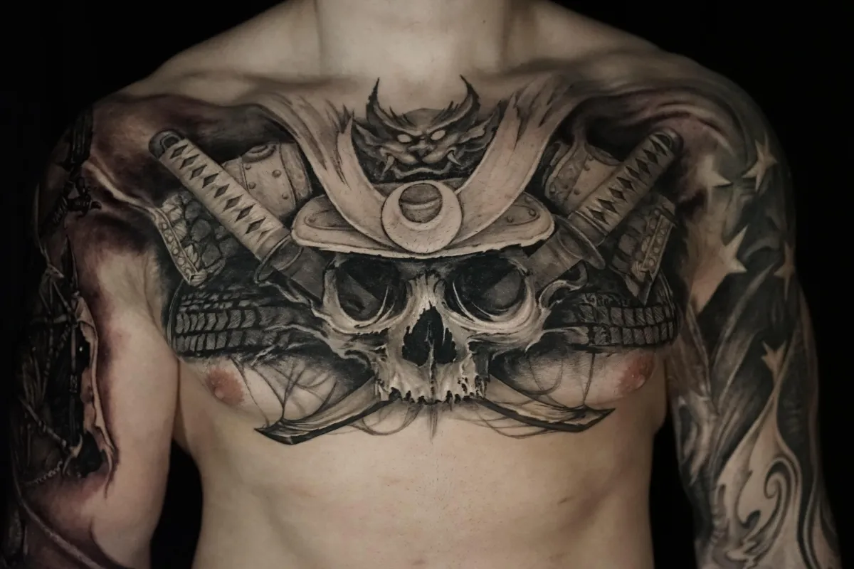 Large black and grey samurai skull chest tattoo with crossed swords and armor details by James Strickland in Missoula Montana
