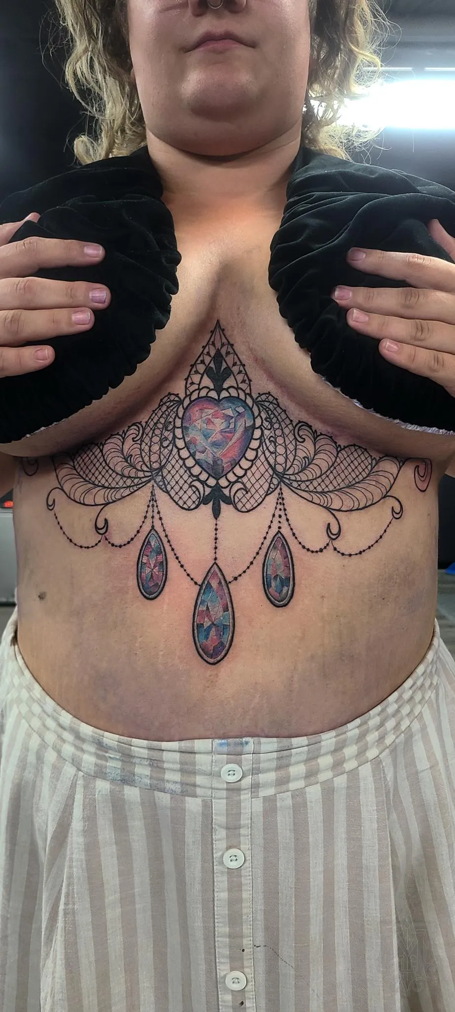 Ornamental underbust tattoo with jewel color accents and lace inspired linework by Mickey Schlick