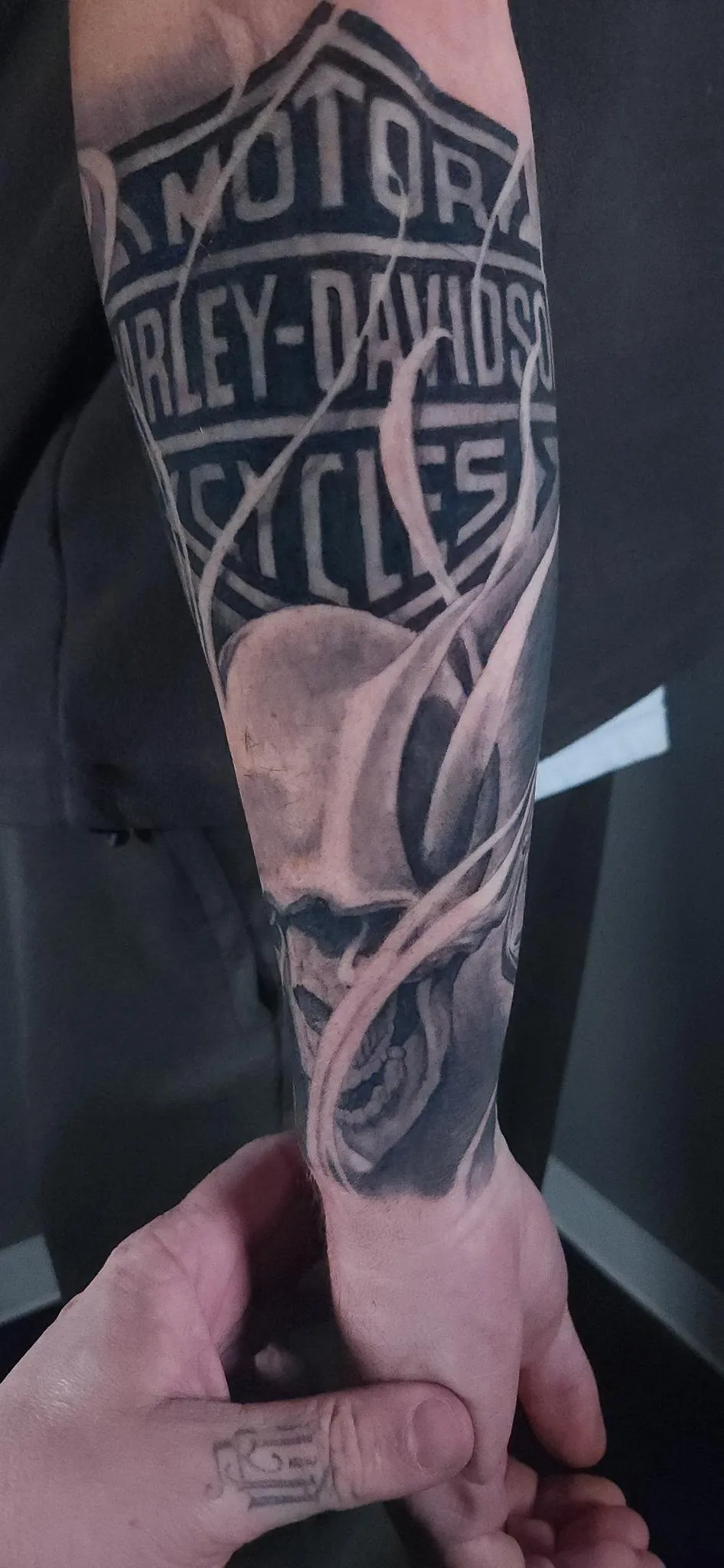 Black and grey Harley Davidson skull and flame forearm tattoo by Mickey Schlick