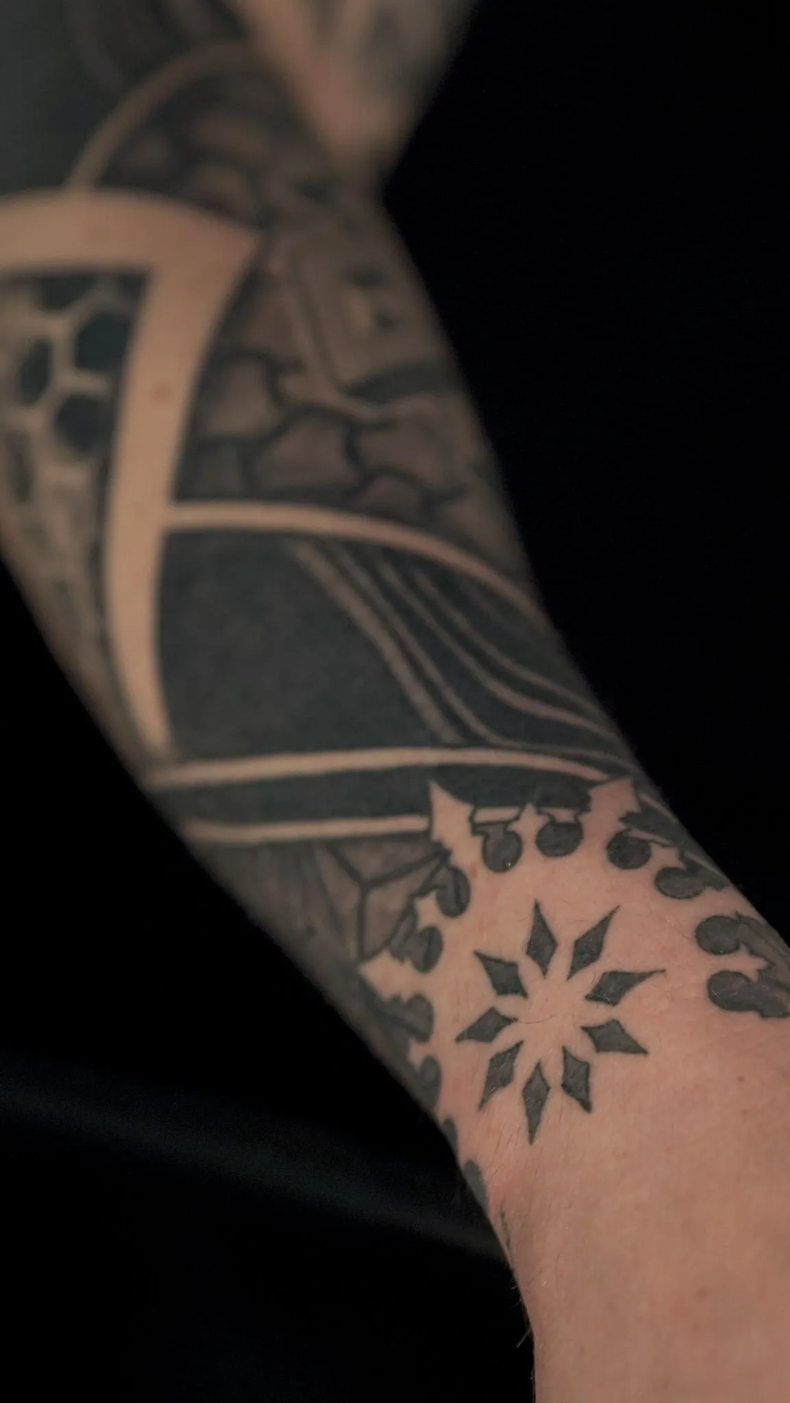 Abstract geometric blackwork sleeve detail with bold negative space by Mickey Schlick