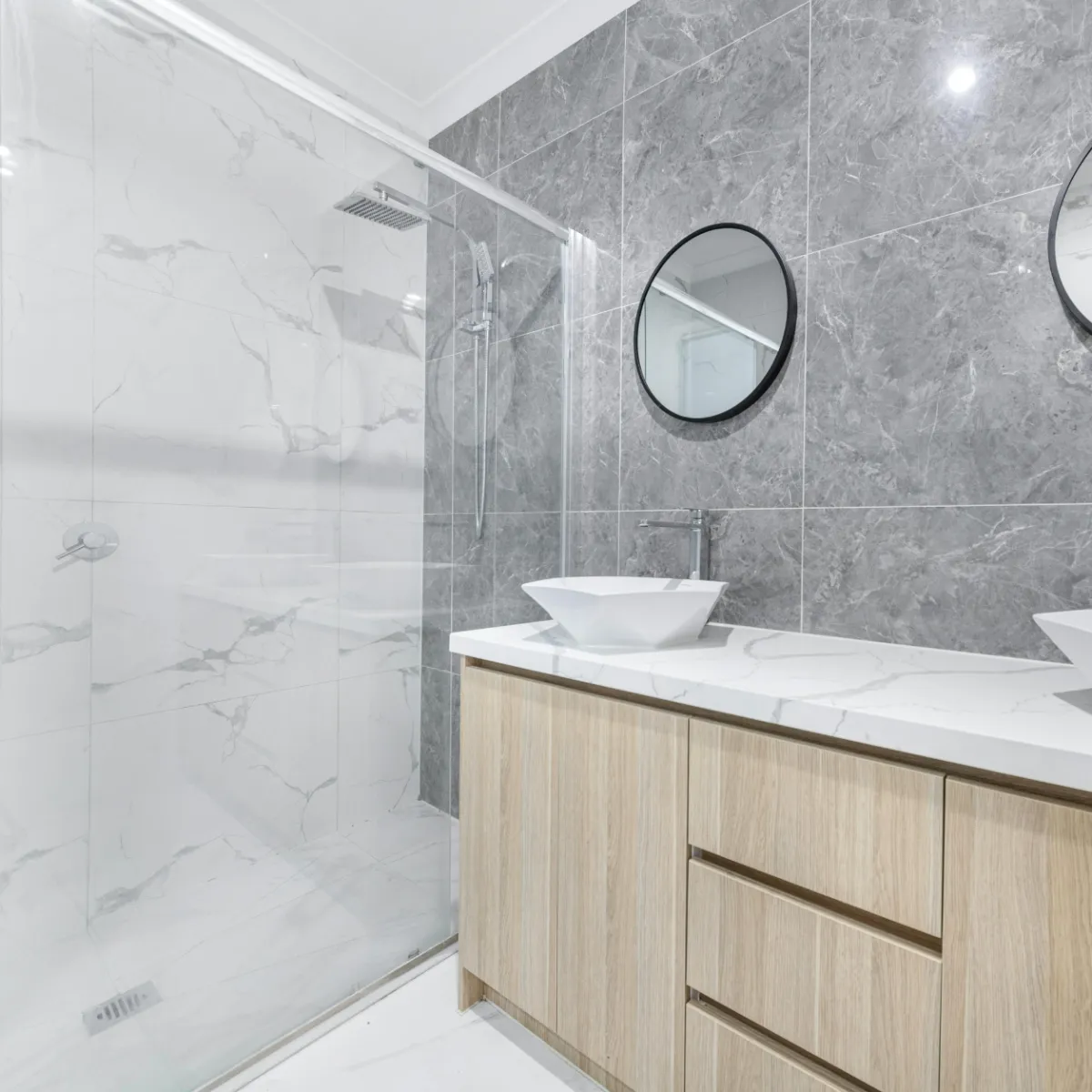 Modern bathroom remodel in Fort Worth featuring marble tile walls, floating vanity, and vessel sink design.