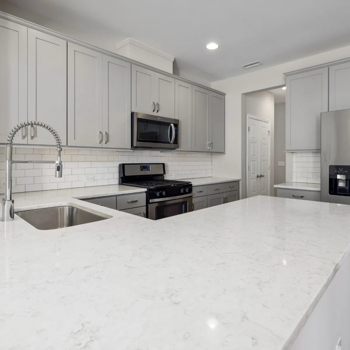 Bright kitchen remodeling project in Fort Worth with white cabinetry, quartz countertops, and stainless steel appliances.