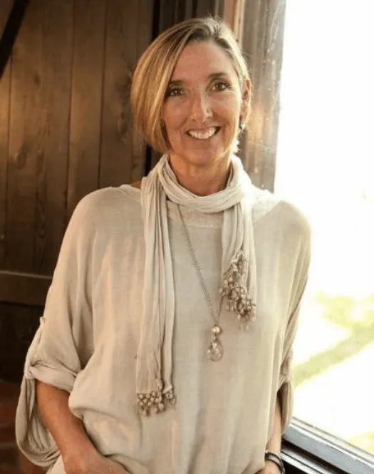 Photo of Michelle Cameron Coulter smiling and leaning against a window