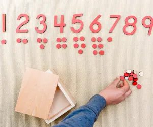 Child writes A in green sand