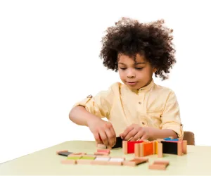Child writes A in green sand