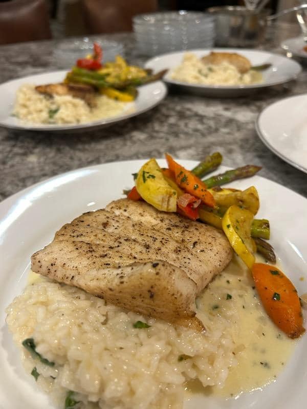 Private chef plated dinner featuring pan-seared fish, creamy risotto, and roasted vegetables prepared by Foodie Call