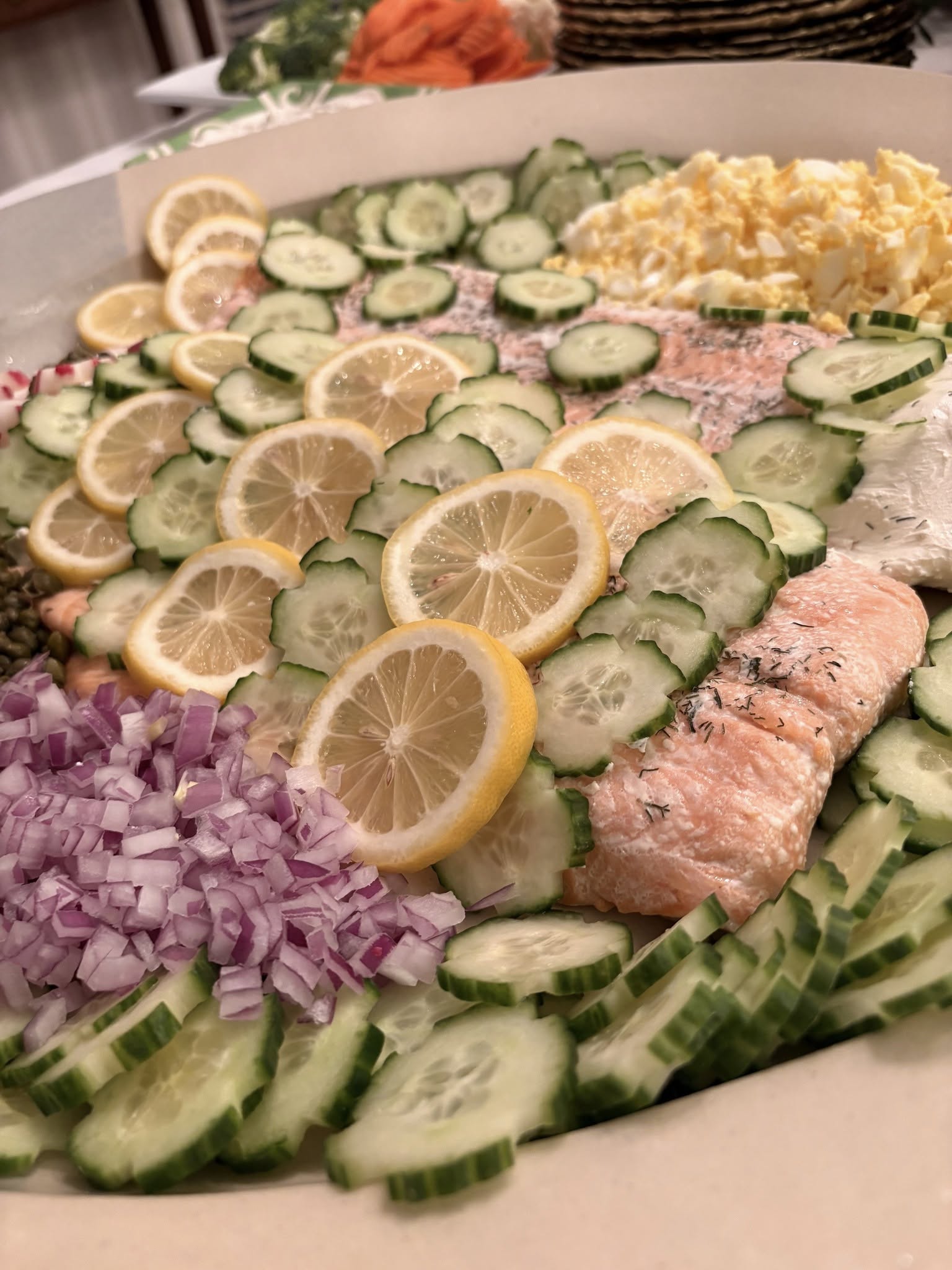 Fresh seafood catering platter with salmon, cucumbers, lemons, and vegetables arranged for Foodie Call catering event