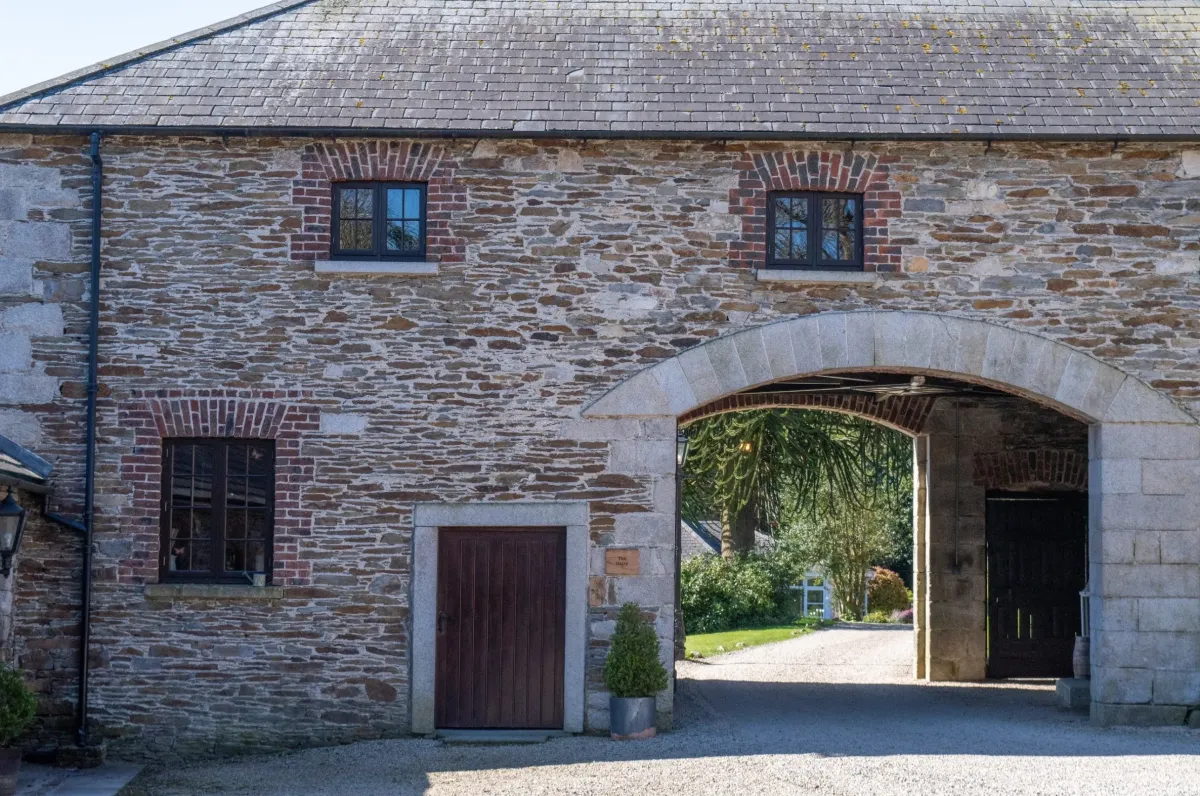 Building entrance at night with cars parked outside.