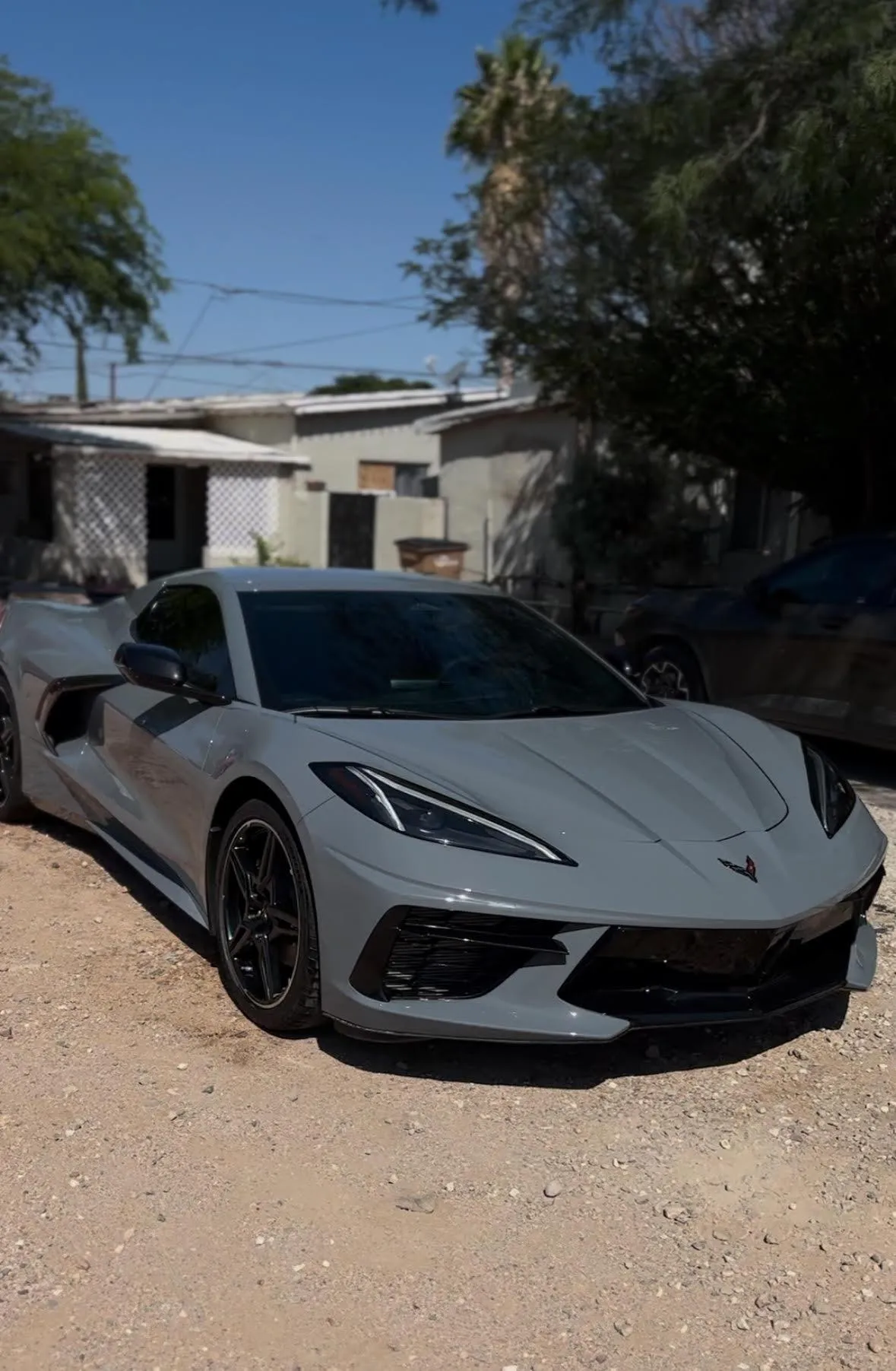 White Corvette with roof down and white Mercedes in the background