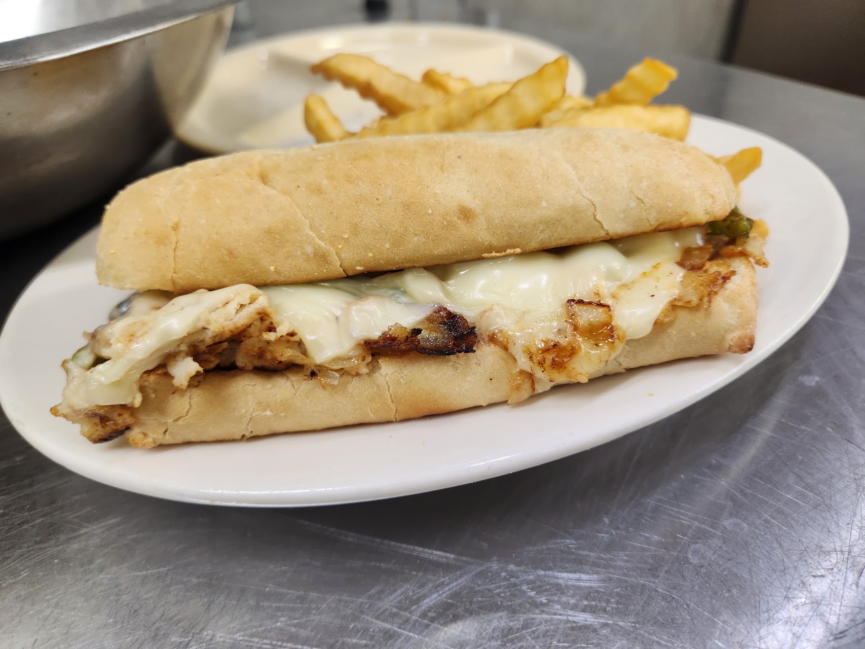 Grilled sandwich on a roll with melted cheese and fries