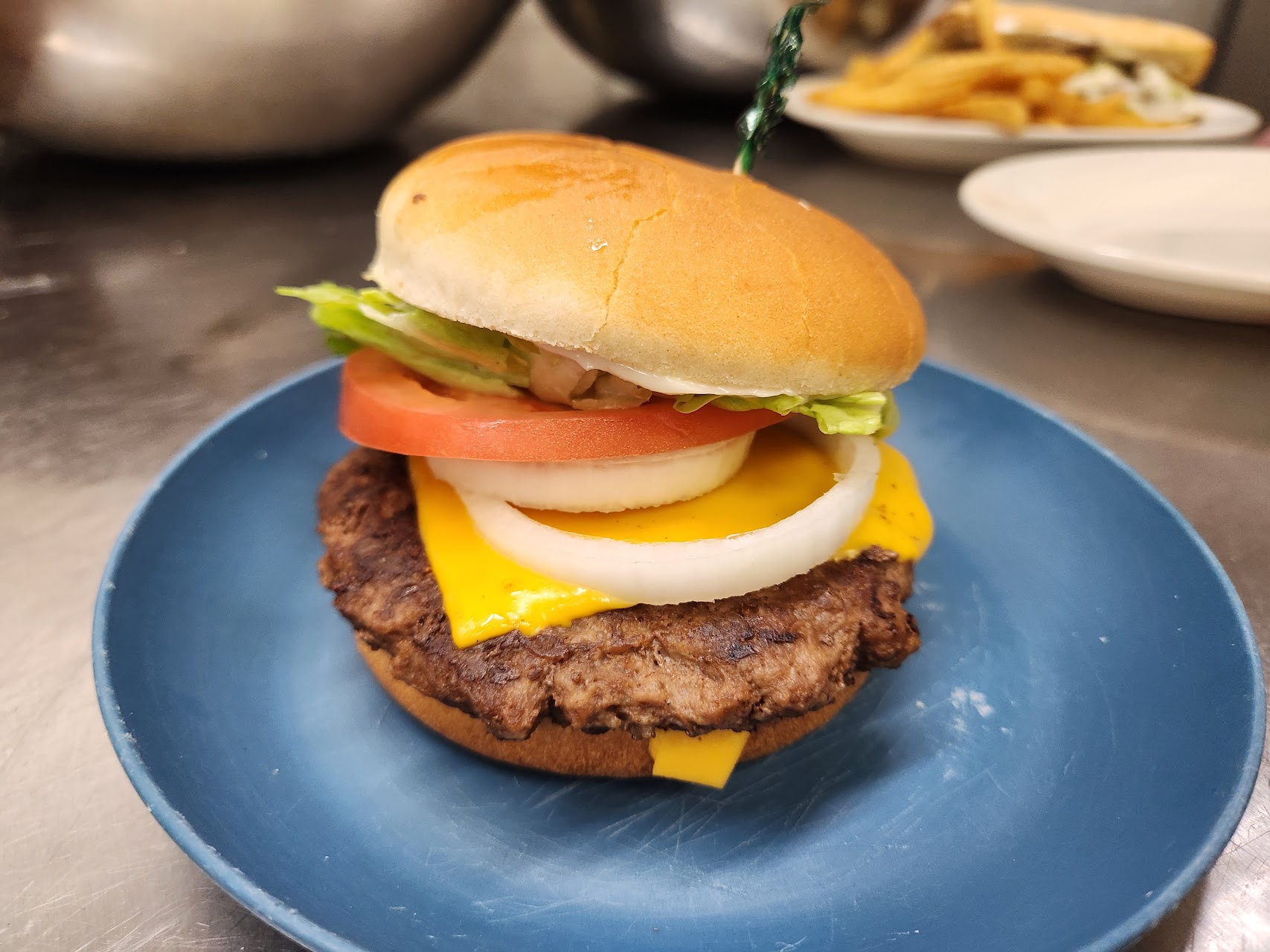 Cheeseburger with lettuce, tomato and onion on a blue plate