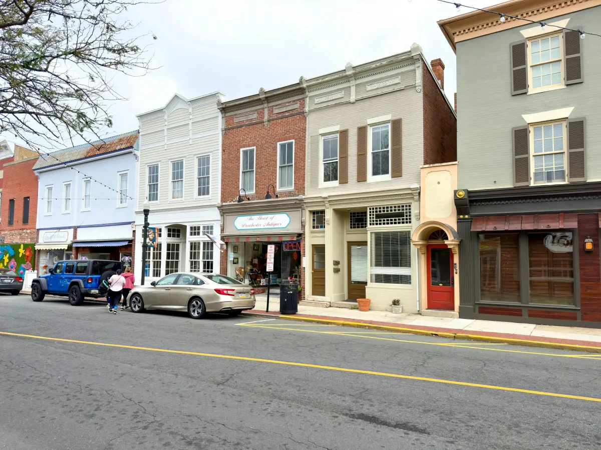 Downtown scene showing buildings, and cars that are in the street parking.