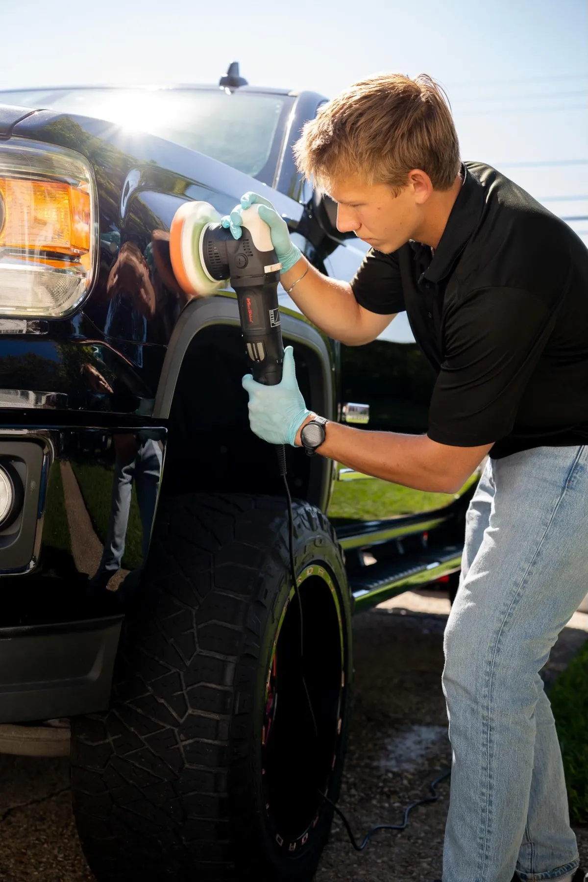 Owner of Elevate Mobile Detailing polishing the paint of a GMC Sierra.