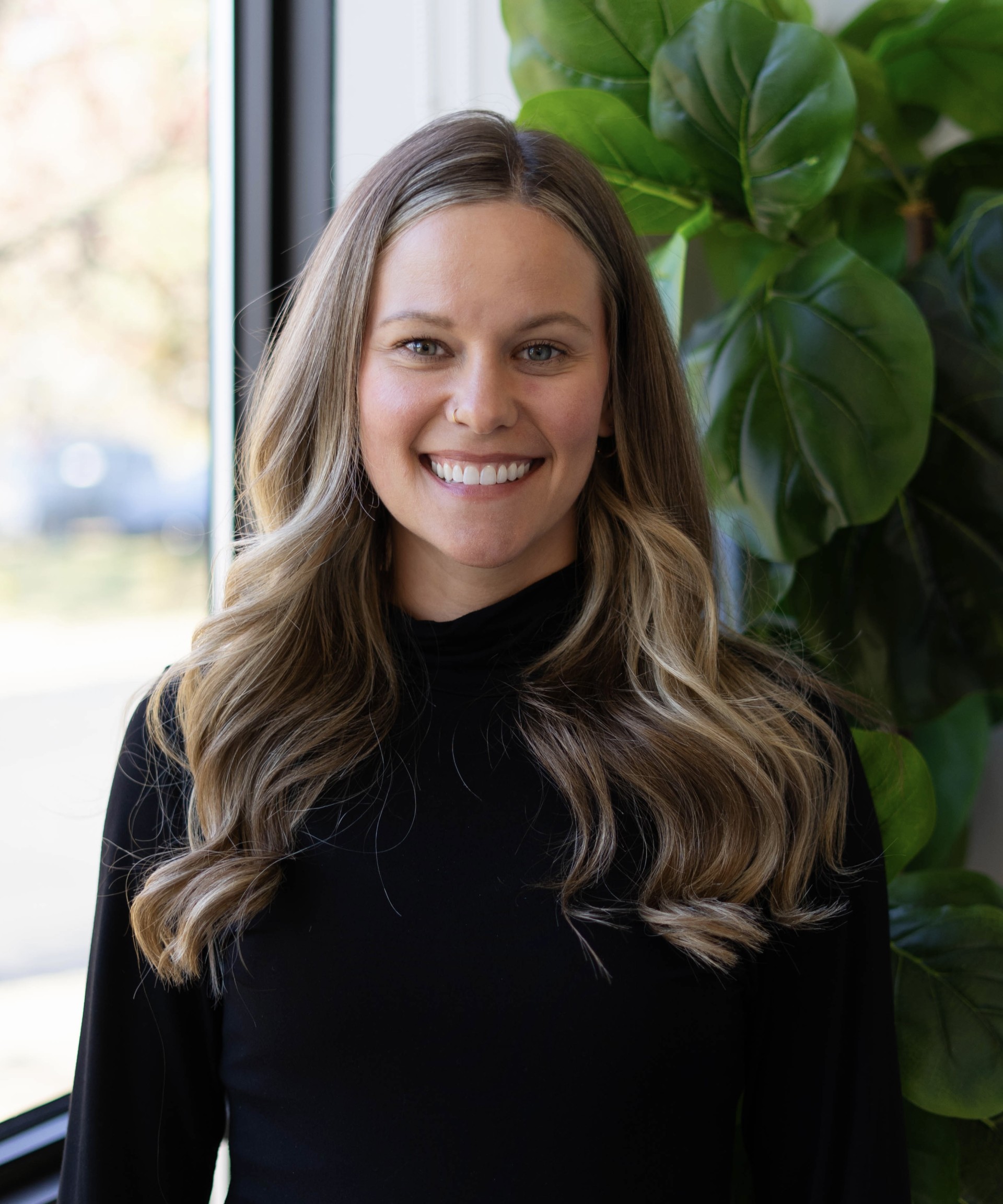 Danielle Leonard, co-owner of Great Lakes Health and Wellness, smiling against a backdrop of greenery, showcasing her passion for health and wellness in Northeast Ohio.