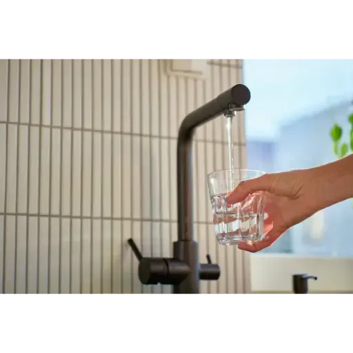 Crystal clear water poured from a modern faucet, demonstrating the effective removal of iron staining and sulfur odors through professional water filtration.