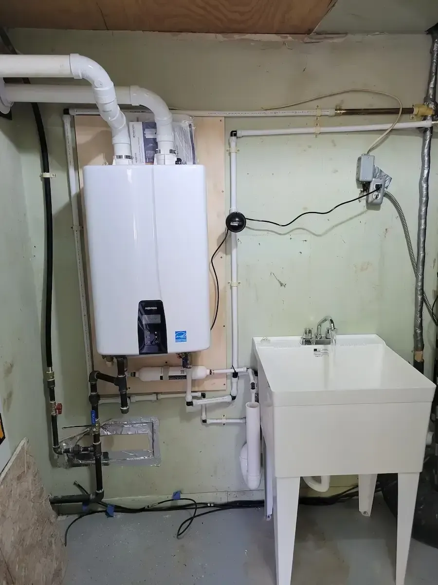 Wall-mounted Navien high-efficiency tankless water heater installed by certified technicians next to a utility sink.