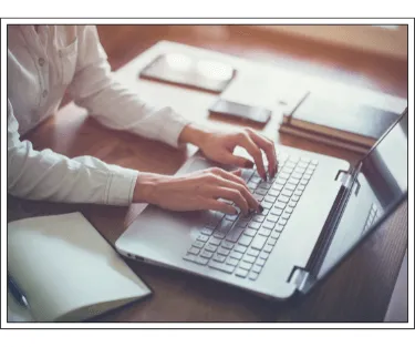 A person typing on a laptop, performing copywriting services.