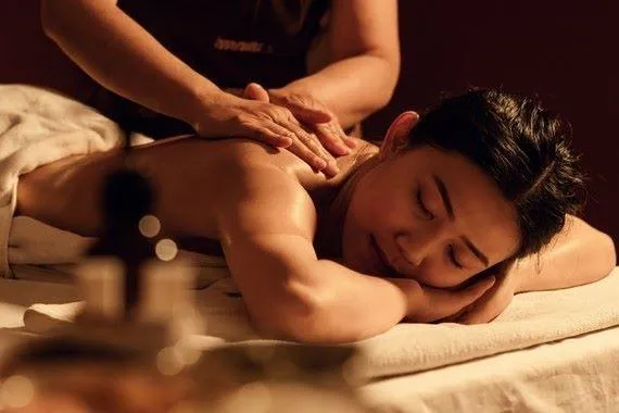 A woman with Asian heritage receives a shoulder and back massage.