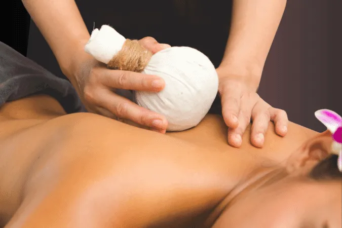 Two hands apply a poultice to a woman's back.