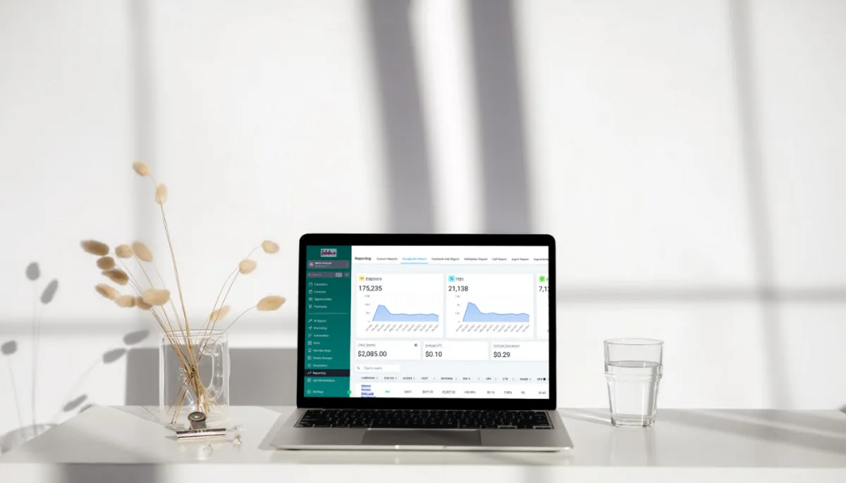 Minimalist white desk with dried floral arrangement, glass of water, and open laptop showing Soleila.io reporting dashboard with website traffic graphs and ad performance data.