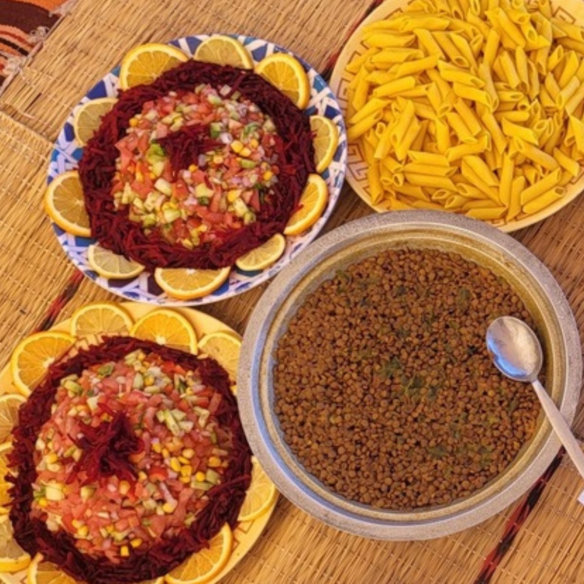 Frisch zubereitetes Essen im Wüstencamp mit Salat, Nudeln und Orangen