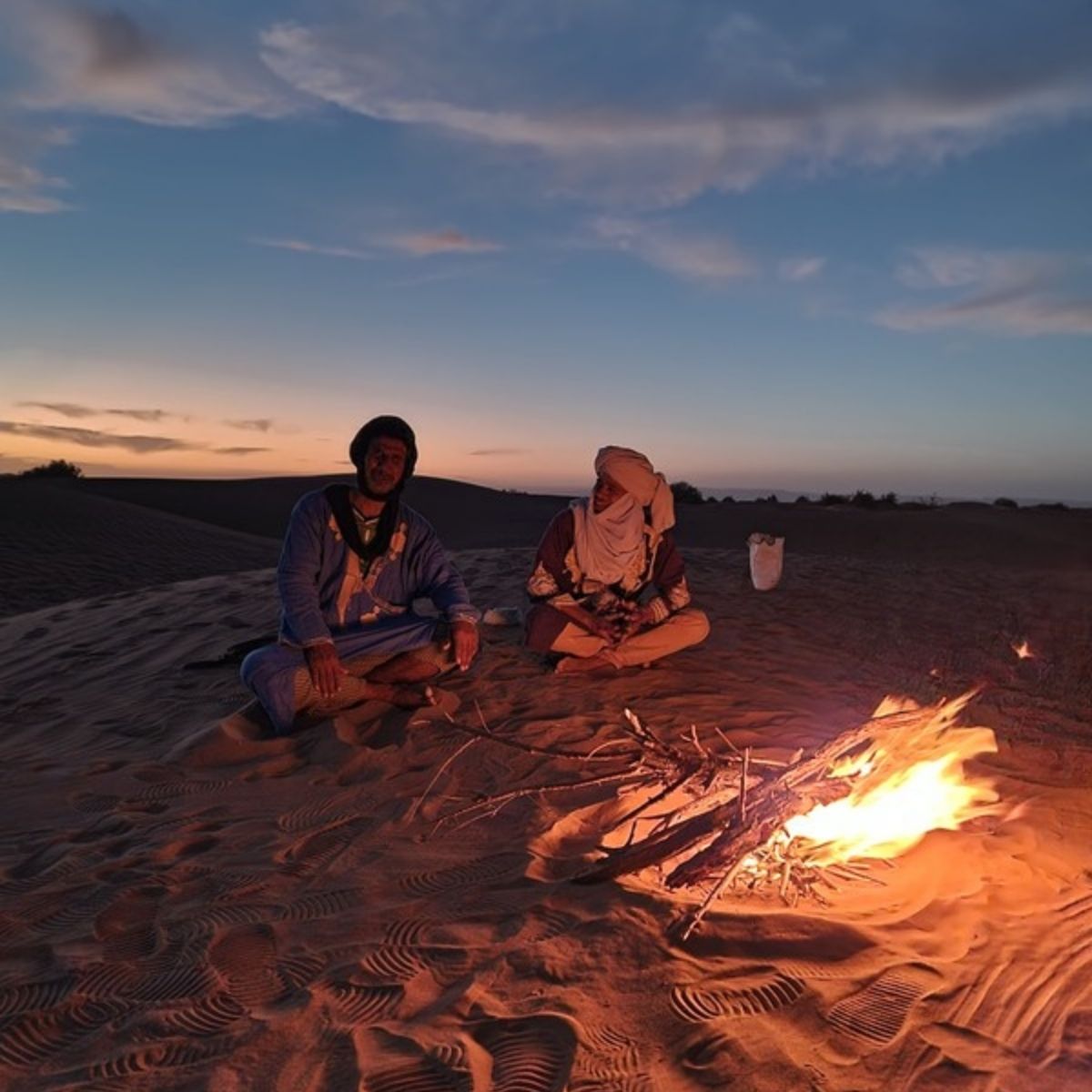 Lokale Guides sitzen bei Sonnenuntergang im Wüstencamp