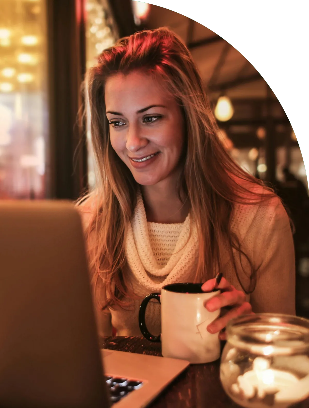 A woman smiling looking at her laptop because she understand spiritual warfare.