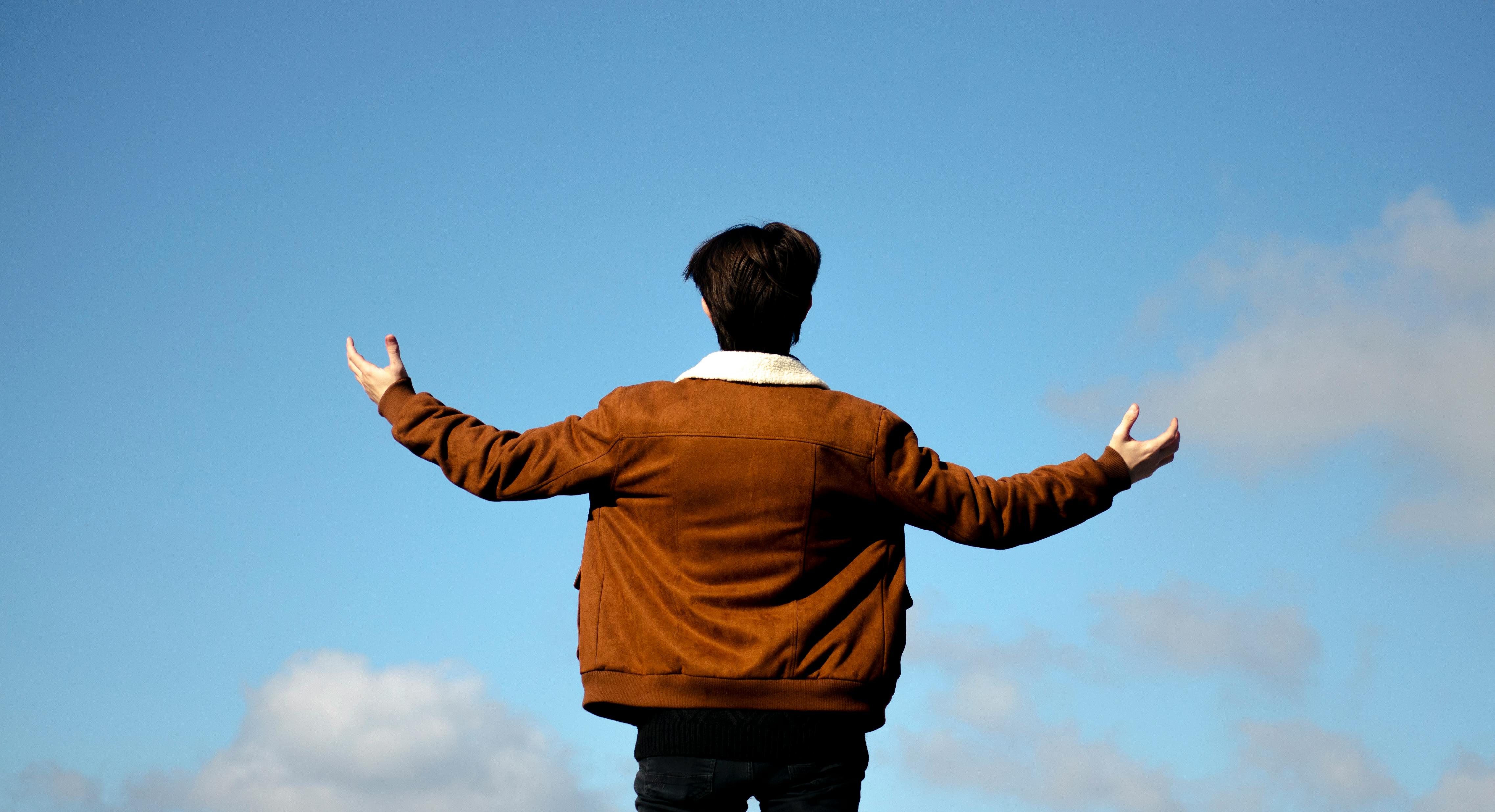 A man stretching his arms to worship God because of freedom.