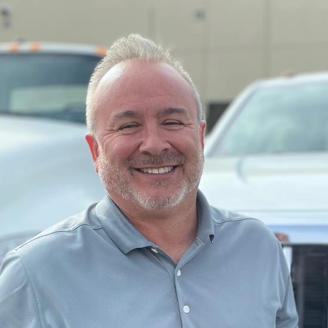 Portrait of Ted Sullivan with trucks behind him