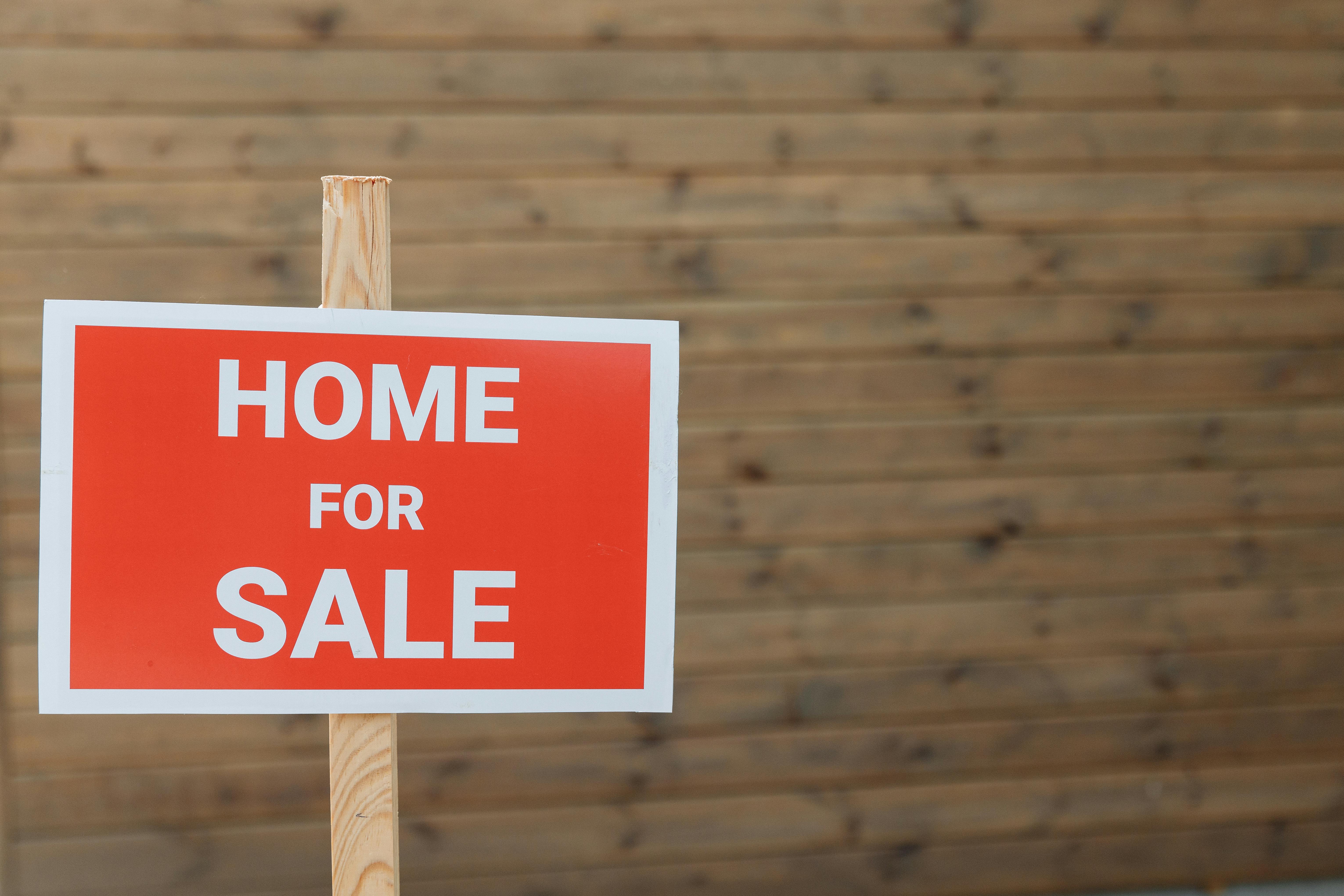 simple red and white home for sale sign on a wooden stick